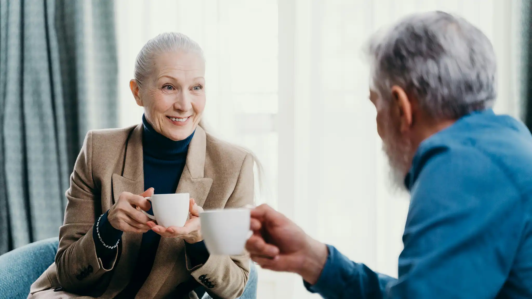 A old happy couple talking while drinking coffee