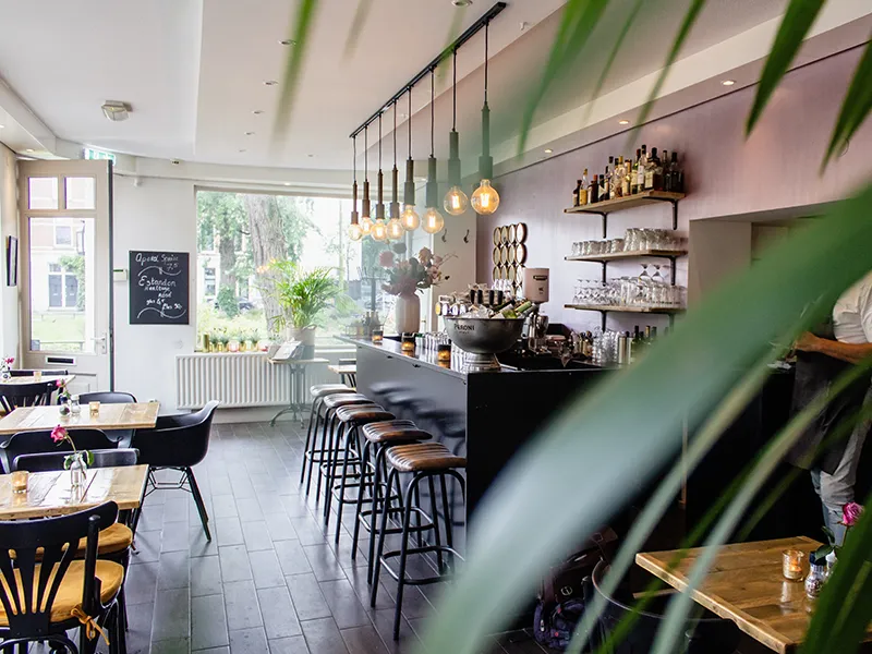 An interior shot of a café with chairs near bar with wooden tables